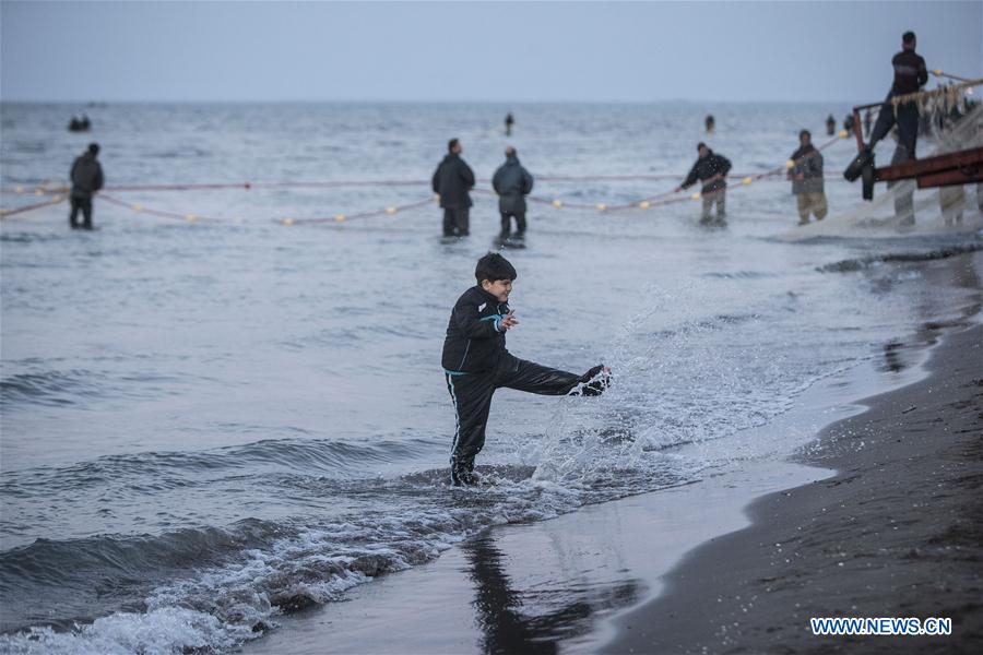 A boy plays with water as Iranian fishermen work at the Caspian sea beach near Anzali Port, northern Iran, on March 27, 2017. (Xinhua/Ahmad Halabisaz) 