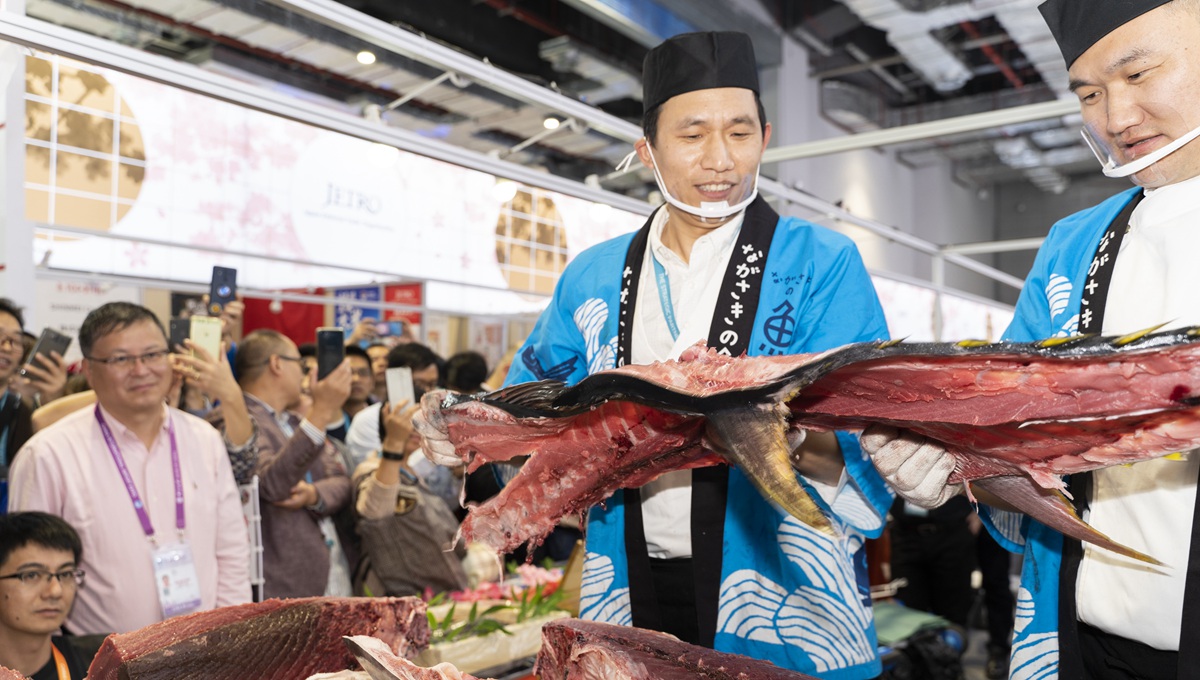 Staff members of Japanese company prepare bluefin tuna meat for visitors at 2nd CIIE