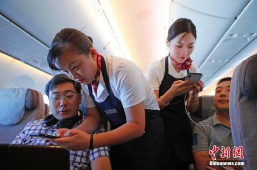 資料圖：乘務(wù)員們在客艙內(nèi)為旅客調(diào)試機上上網(wǎng)功能。<a target='_blank' ><p  align=
